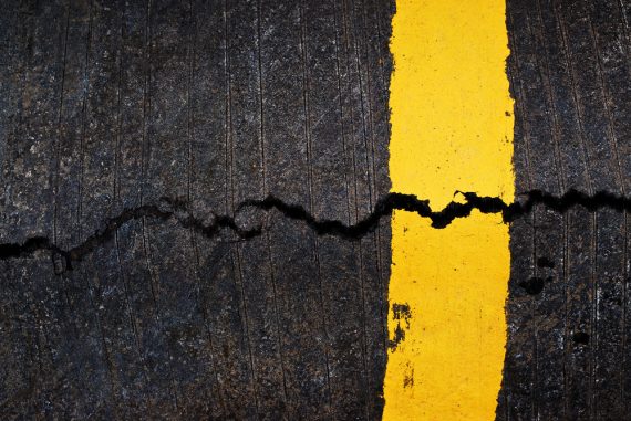 Yellow line on cracked asphalt road