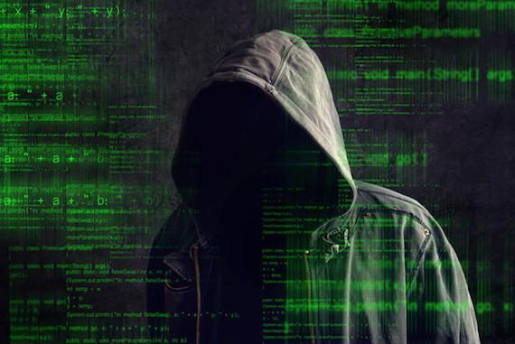 Faceless hooded anonymous computer hacker with programming code from monitor, dark web concept